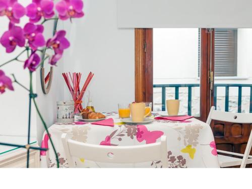 トレドにあるApartamentos Rey Moroの白いテーブルクロスと紫色の花が飾られたテーブル