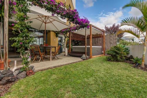 a house with a garden with a table and purple flowers at epicenter SANTACRUZ in Lagoa