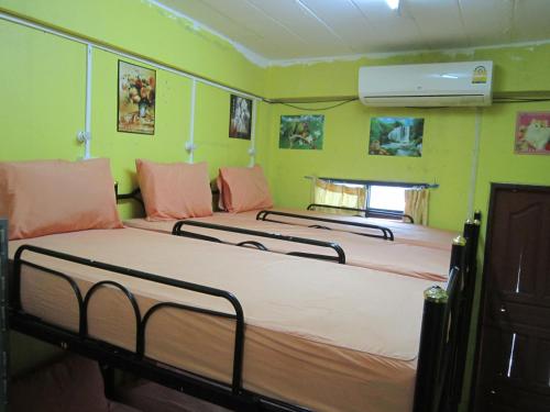 três camas num quarto com paredes verdes em Lucky Homestay em Haad Rin