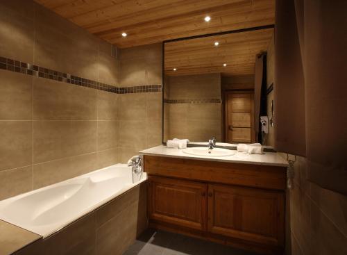 bagno con vasca, lavandino e specchio di Chalet des Neiges Hermine a Val Thorens