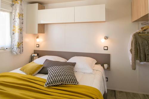 a bedroom with a bed with two pillows on it at Camping Les Chênes Verts in Meschers-sur-Gironde