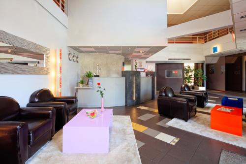 a waiting room with leather chairs and a table at Hôtel & Résidence Octel in Portet-sur-Garonne