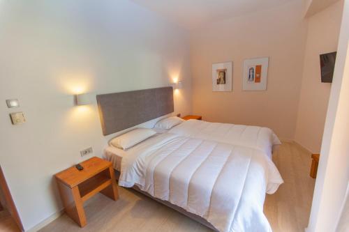 a bedroom with a white bed and a wooden table at Antikyra Beach Hotel in Antikyra