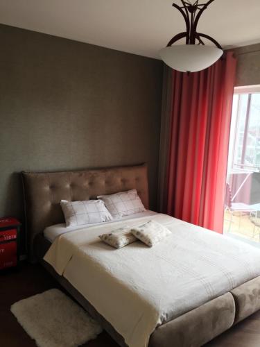 - une chambre avec un grand lit et un rideau rouge dans l'établissement Apartament Birutes 22, à Klaipėda
