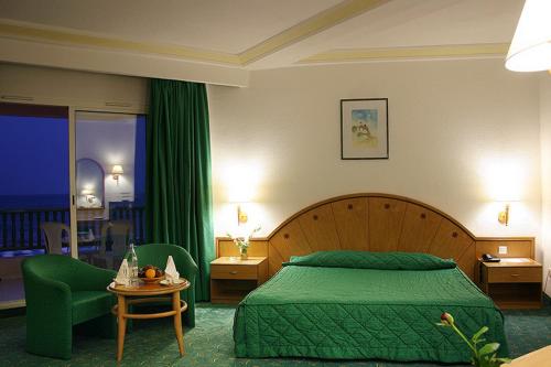 a bedroom with a green bed and a green chair at El Mouradi Hammamet in Hammamet