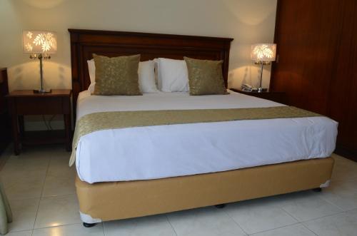 uma cama grande num quarto de hotel com duas lâmpadas em Grand Isabella Residences em Cebu