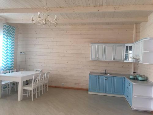 a kitchen with blue cabinets and a white table at Villa Blumarine in Zatoka