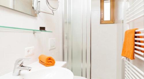 ein weißes Bad mit einem Waschbecken und einer Dusche in der Unterkunft Frühstückspension Rehwinkl in Sölden