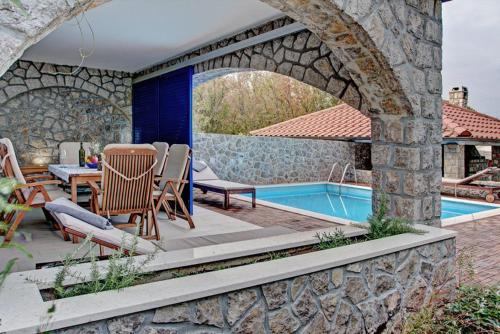 eine Terrasse mit einem Tisch und Stühlen neben einem Pool in der Unterkunft Apartments Petra in Njivice