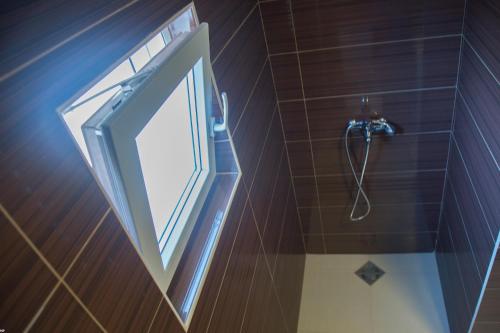 a bathroom with a shower with a window and a mirror at Del Mar Apartments in Čanj