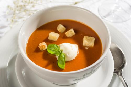 a bowl of soup on a plate with a spoon at Sporthotel Austria in Sankt Johann in Tirol