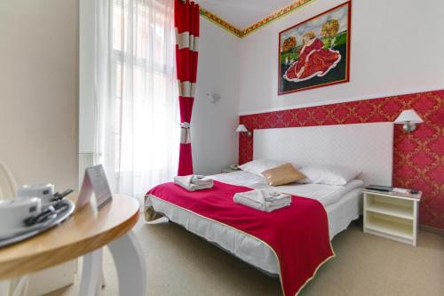 a bedroom with a red and white bed with a table at Małopolanka & Spa in Krynica Zdrój