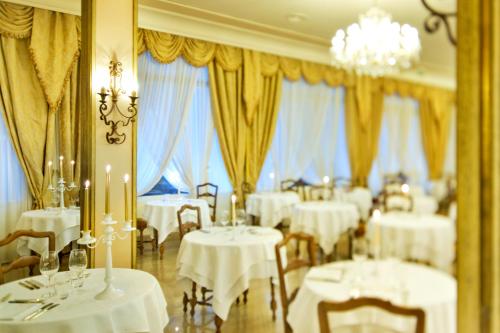 a restaurant with white tables and chairs and windows at Hotel La Residence & Idrokinesis in Abano Terme