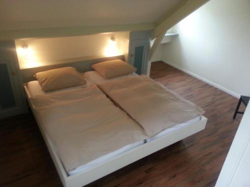 een bed met witte lakens en kussens in een kamer bij Hoeve Schoonzicht in Wijlre