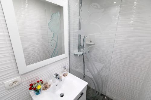 uma casa de banho branca com um lavatório e um chuveiro em Rose Apartment em Split