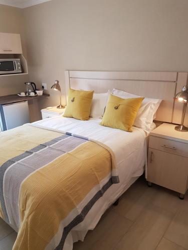 a bedroom with a large bed with yellow pillows at LightStone Guesthouse in Centurion