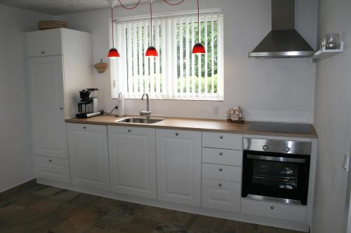 a kitchen with white cabinets and a sink and a window at Sov Godt i Arnborg Bed & Breakfast in Arnborg