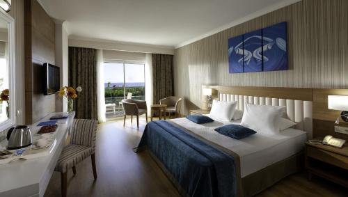 a hotel room with a bed and a desk and a room at Adalya Ocean Deluxe in Side