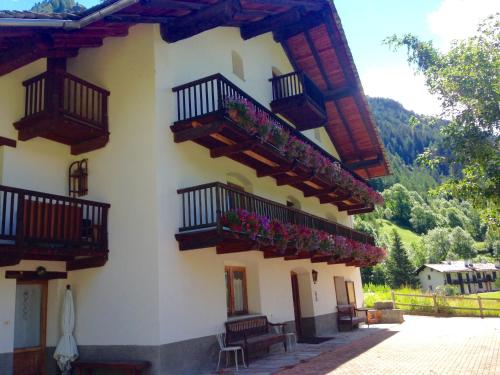 un edificio con balconi e fiori di Flora Alpina apartments-Residenza Verdebjo a Gressoney-Saint-Jean