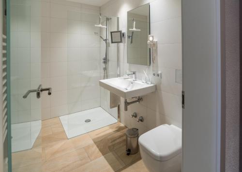 a white bathroom with a sink and a toilet at Brennereihotel Sponsel in Kirchehrenbach