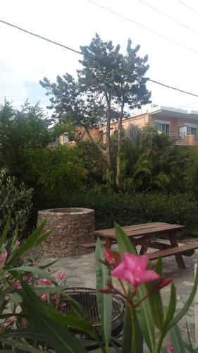 una mesa de picnic en un jardín con una flor rosa en Stelios Rooms, en Palaiochóra