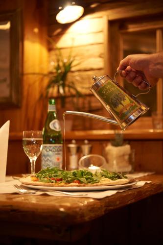 a person pouring a drink into a pizza on a table at Hotel Happy Filzmoos in Filzmoos