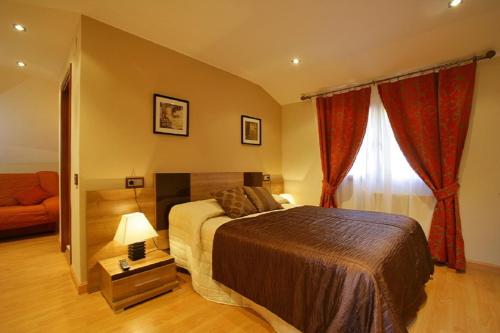 a bedroom with a bed and a couch and a window at Hotel Peñagrande in Cangas del Narcea