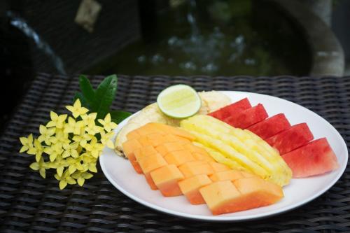 a white plate of fruit on a table at Wijaya Guesthouse in Canggu