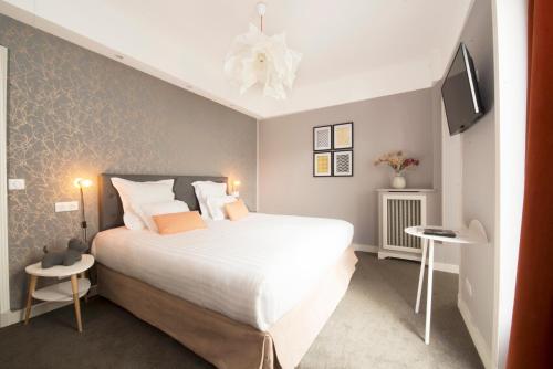 a bedroom with a large white bed and a tv at Hôtel des Batignolles in Paris