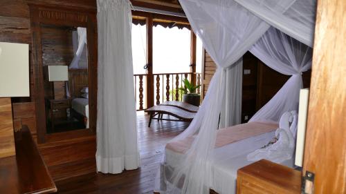 a bedroom with a canopy bed and a balcony at Lakaz An Bwa in La Digue
