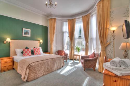 a bedroom with a bed and a chair and windows at The Iona in Torquay