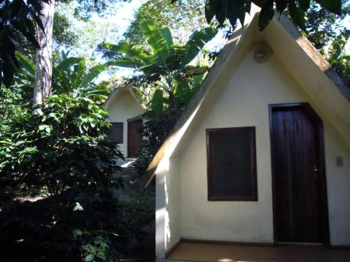 una pequeña casa blanca con puerta marrón en Chalés Sítio do Alemão en Ubajara