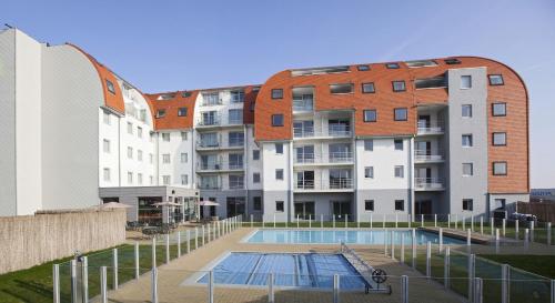 an apartment building with a swimming pool in front of it at Holiday Suites Zeebrugge in Zeebrugge