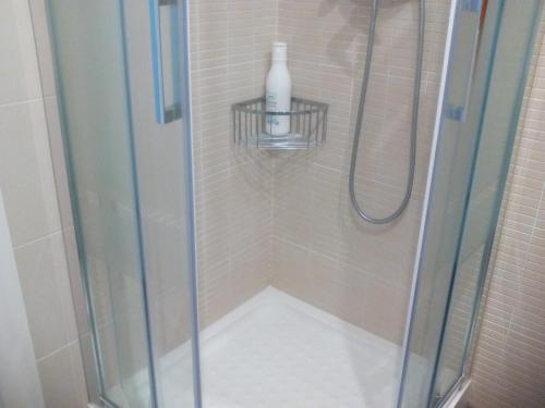 una ducha con puerta de cristal y una botella en un estante en New La Granada, en Granada