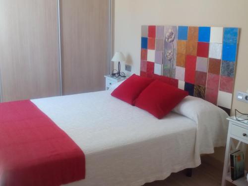 Un dormitorio con una cama con almohadas rojas. en New La Granada, en Granada