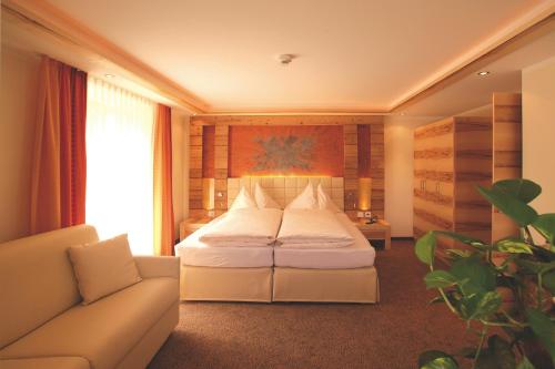 a hotel room with a bed and a couch at Hotel Garni Muttler Alpinresort & Spa in Samnaun