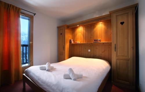 um quarto com uma cama com duas toalhas brancas em Chalet des Neiges Oz en Oisans em Oz