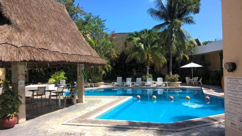 una piscina con sillas y techo de paja en Hotel Plaza Caribe, en Cancún