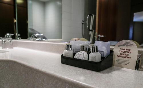 a bathroom sink with a tray of soap and a mirror at Alona Hotel in Motherwell