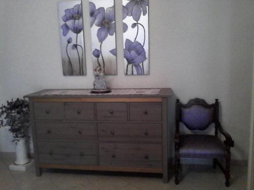 a dresser with a chair and two paintings on the wall at LA CASA DEI MASUE' in Alba