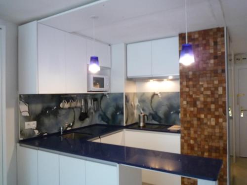 a kitchen with white cabinets and blue counter tops at Tramuntana in Platja  d'Aro