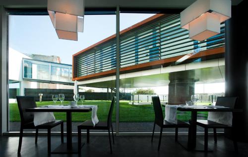a dining room with two tables and chairs and a large window at Design & Wine Hotel in Caminha