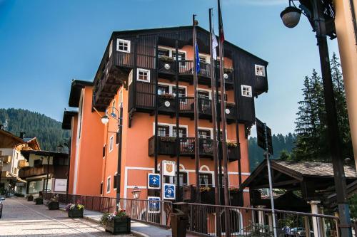 a tall orange building with balconies on a street at Hotel Posta R.T.A. in Madonna di Campiglio
