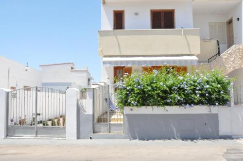a white house with a fence and a planter with flowers at Due Passi Dalla Spiaggia in Lido Marini