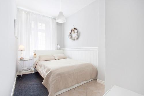 a white bedroom with a bed and a window at The Heart of Old Town Apartments in Gdańsk