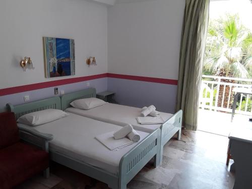 two twin beds in a room with a window at Zontanos Studios & Apartments in Poros