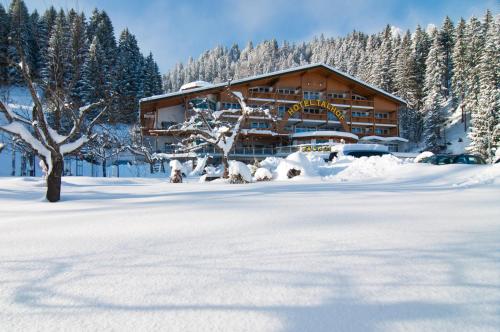 a large wooden building in the snow with trees at Hotel Talhof Garni&more in Wängle bei Reutte in Reutte