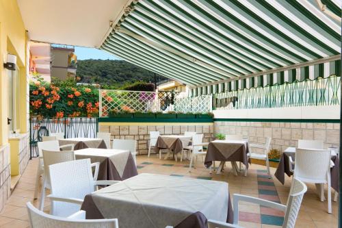 Hotel Viola في جيتا: مطعم بطاولات بيضاء وكراسي وزهور