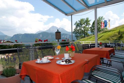 two tables with red table cloths on a patio with mountains at Hotel Talhof Garni&more in Wängle bei Reutte in Reutte