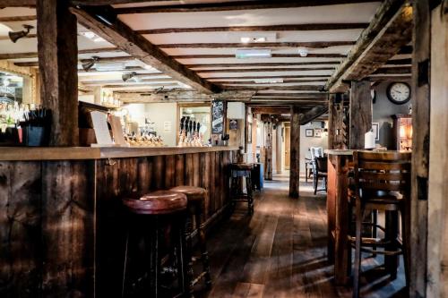 a bar with wooden walls and wooden stools at The Crown Inn in Bishops Waltham